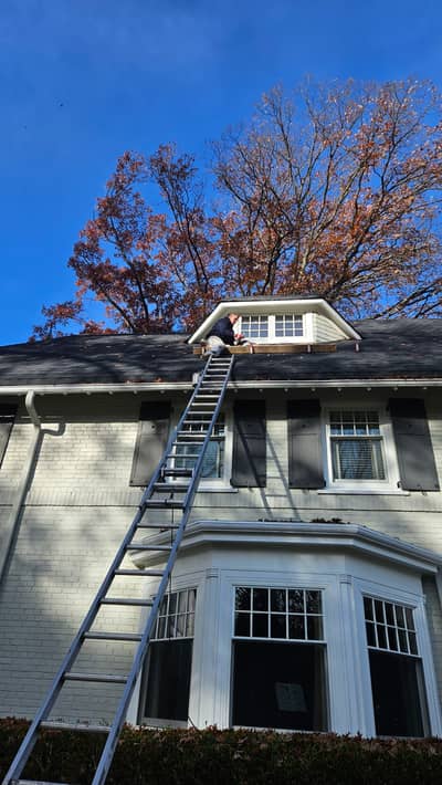House exterior with an extension ladder leaning against the white brick siding.
