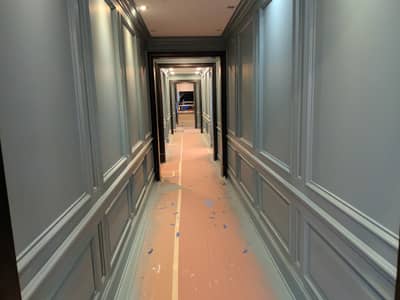 Long hallway with white-painted walls, decorative trim, and tan flooring.