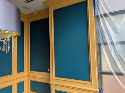 Room interior with teal-painted walls and wooden-framed window panels mid-preparation.