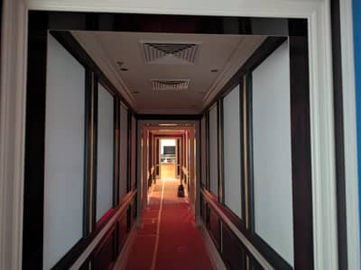 Long hallway with red carpet, dark painted walls, and recessed lighting.