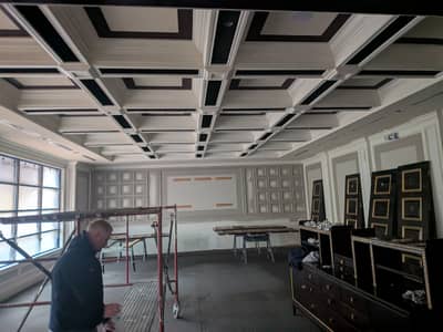 Commercial space interior with geometric coffered ceiling design in gray and white.