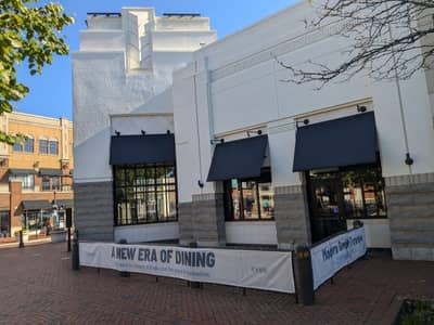 Commercial storefront with blue retractable awnings and sand-colored facade.
