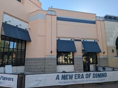 Commercial building with blue awnings and tan painted facade.