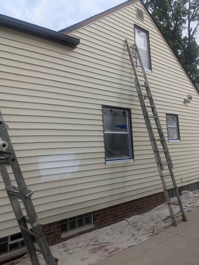 House exterior with siding and aluminum extension ladder leaning against the wall.