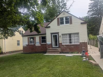 House exterior with split white and tan siding and green lawn.
