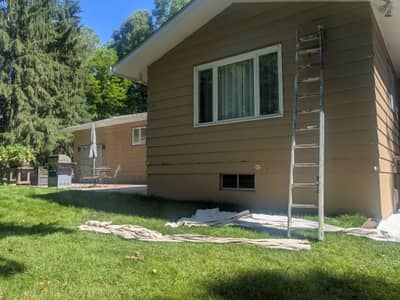 House exterior with tan-colored siding and aluminum ladder nearby.