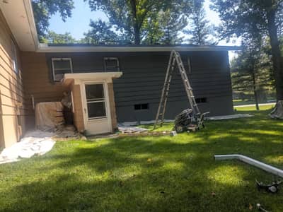 House under renovation with exposed metal framing and boarded window openings.