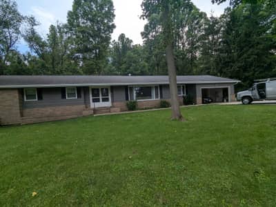 Single-story gray brick house with garage and landscaping.