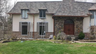 Two-story stone and white facade house with rounded arch entryway.
