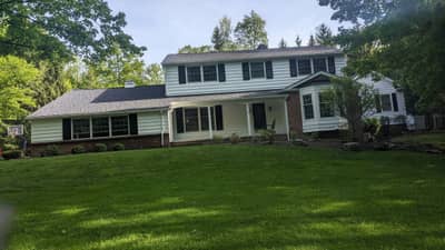 Large two-story colonial-style house with green-tinted exterior.