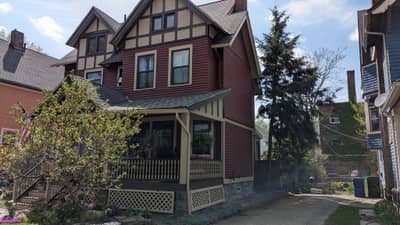 Two-story red-brick house with black and white trim and covered porch.