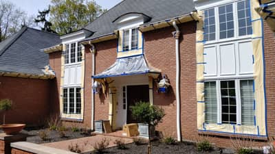 White brick house exterior with covered entry and architectural detailing.