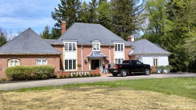 Large cream-colored brick house with dual gables and driveway.