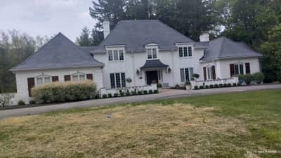 Large two-story white colonial house with multiple gables and centered entry.
