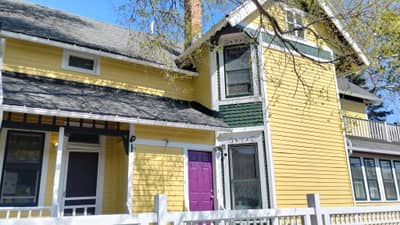Yellow house with dark purple second-story section and white trim.
