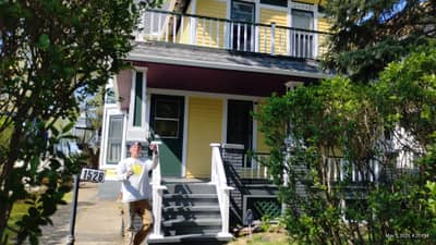 Two-story house with yellow upper and dark lower sections, front porch.