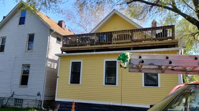 Yellow house with dark trim and beam supports.