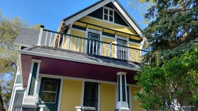 Yellow two-story house with white trim and dark roof.