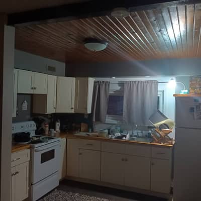 Kitchen with light wood ceiling, white appliances, and large window.