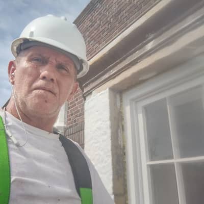 Person wearing white hard hat and safety vest posing outdoors.