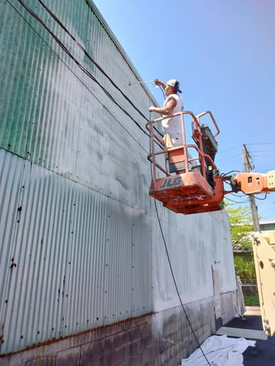 Commercial building with orange scissor lift for exterior painting work.