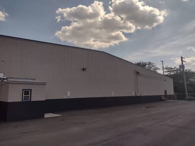 Commercial warehouse building with gray metal siding and dark stripe.