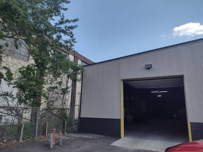 Commercial building with gray metal walls and overhead garage door.