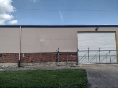 Commercial building with tan metal and brick foundation.