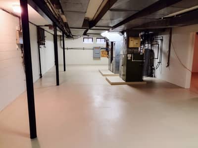 Interior basement or industrial workspace with structural supports, exposed pipes, and concrete flooring.