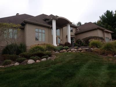 Exterior of a residential house with beige siding and landscaped front yard.