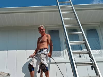 Exterior of a residential building with a worker on a ladder performing exterior maintenance.