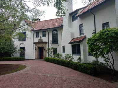 Exterior of a Mediterranean-style white house with red tile roof and driveway.