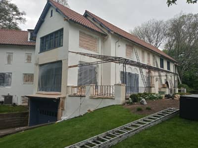 Exterior of a Mediterranean-style house with protective coverings on the balcony.