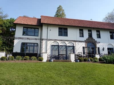 Exterior of a Mediterranean-style house with red tile roof and manicured landscaping.