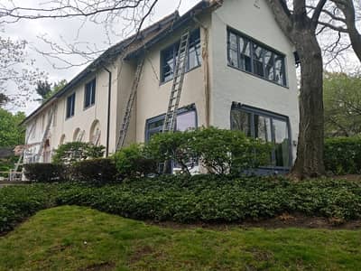 Exterior of a cream-colored house with exterior stairs and ivy climbing the walls.