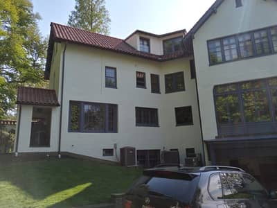 Exterior of a multi-story residential house with red tile roof and multiple windows.