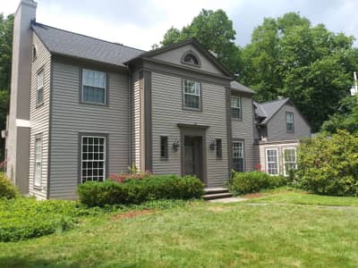 Exterior of dark gray residential house with front entrance and front yard landscaping.