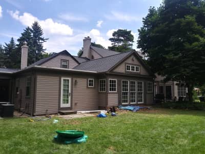 Exterior of tan residential house with multiple gables and mature trees.
