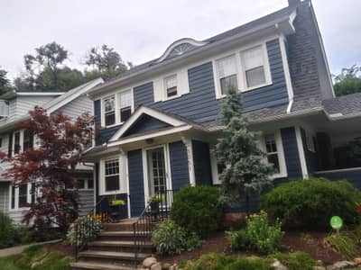 Blue painted house with white trim, shutters, and landscaped front entry.