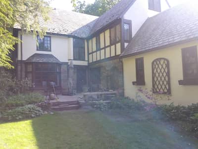 Yellow painted house with black and white decorative timber frame details and courtyard.