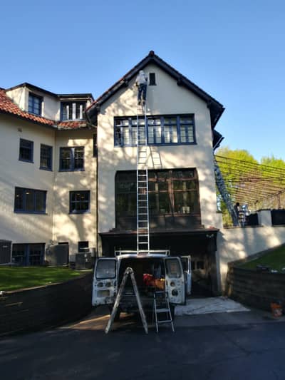 House facade with work vehicle and ladder setup positioned for exterior work.
