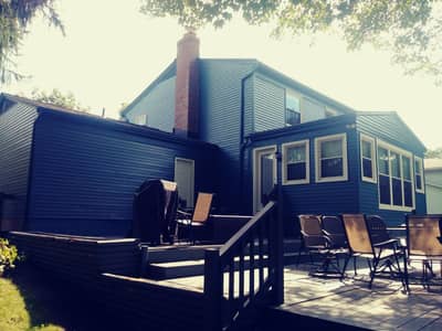 Dark blue painted house with white trim and landscaped foundation plantings.