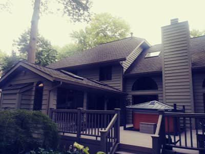 Brown painted house with stone veneer accents and natural landscaping.