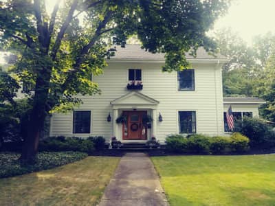White painted house exterior with manicured lawn and foundation plantings.