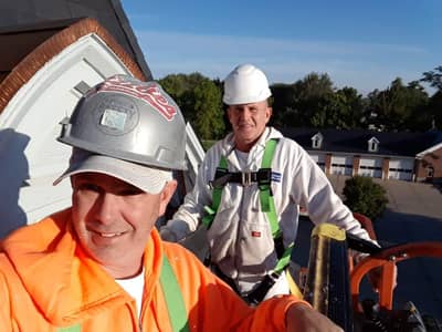 Two construction workers in safety helmets and high-visibility apparel outdoors.