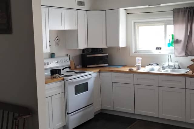 The same kitchen after painting, with white cabinets and a white ceiling.