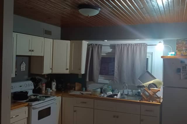 A kitchen before painting, with cream cabinets and a dark wood-plank ceiling.
