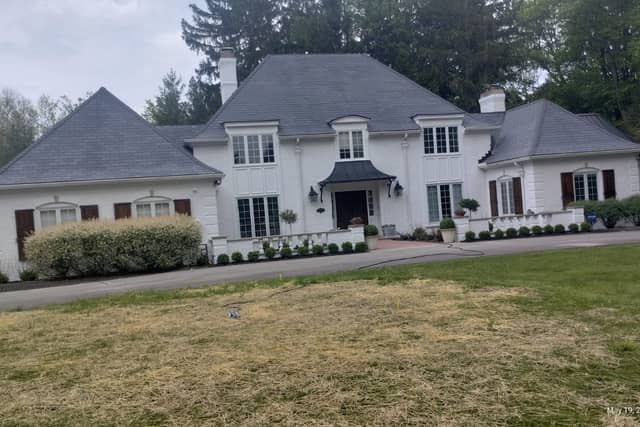 A wide view of a white painted-brick house with a slate roof and dark shutters.