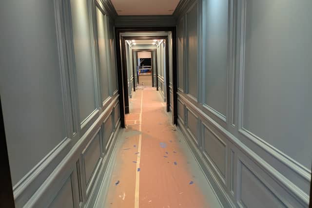 A panelled corridor painted pale green, with the floor covered in protective paper.